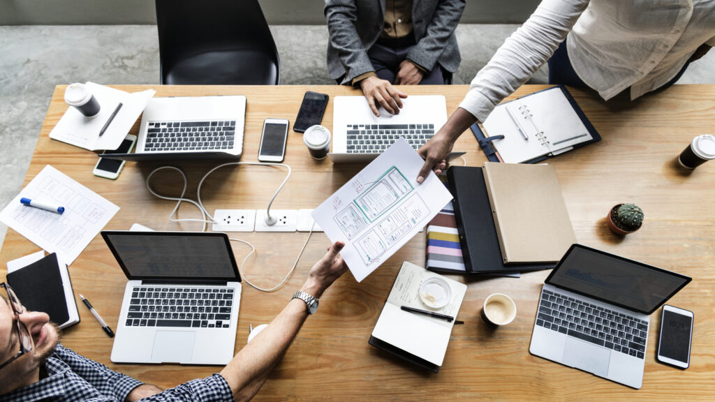 mesa com varios projetos de marketing e profissionais trabalhando em Agência digital